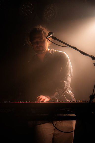 Ein Musiker spielt Keyboard in einem schwach beleuchteten Raum.