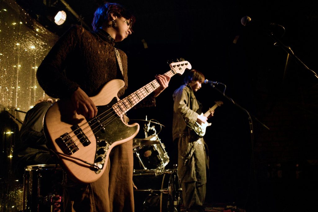 Zwei Musiker auf der Bühne, einer spielt Bass, der andere Gitarre.