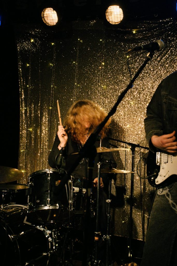 Ein Schlagzeuger spielt leidenschaftlich, goldene Lichter im Hintergrund.