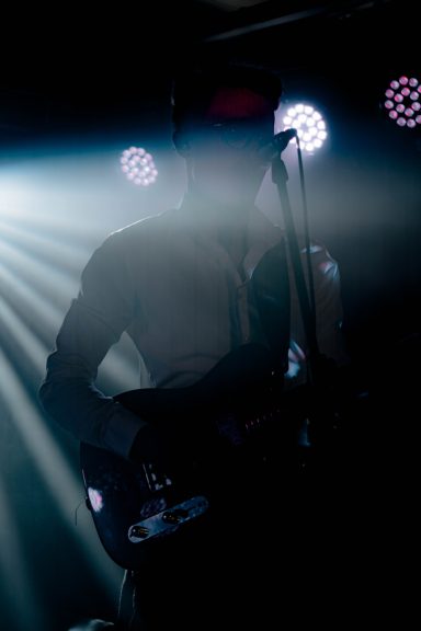 Silhouette eines Musikers mit Gitarre, umgeben von Lichstrahlen.